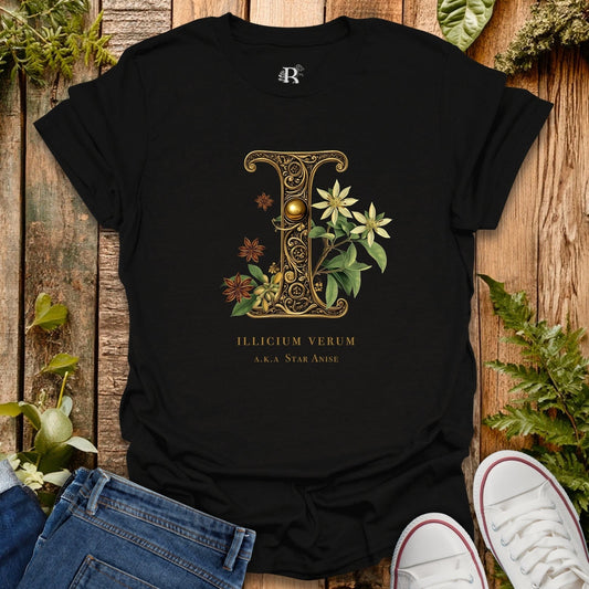 Black t-shirt with decorative letter 'I' design on a wooden surface with plants.