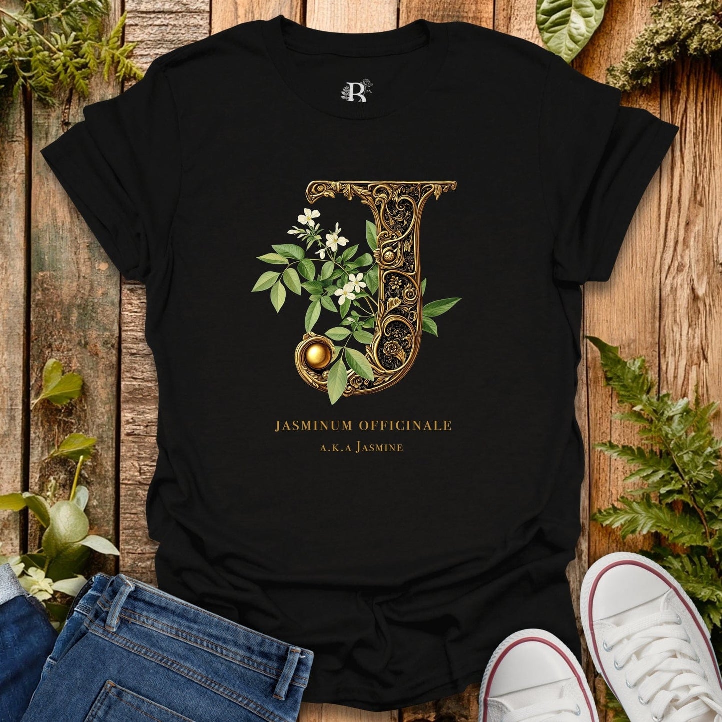 Black t-shirt with decorative letter 'J' design on a wooden surface with plants.