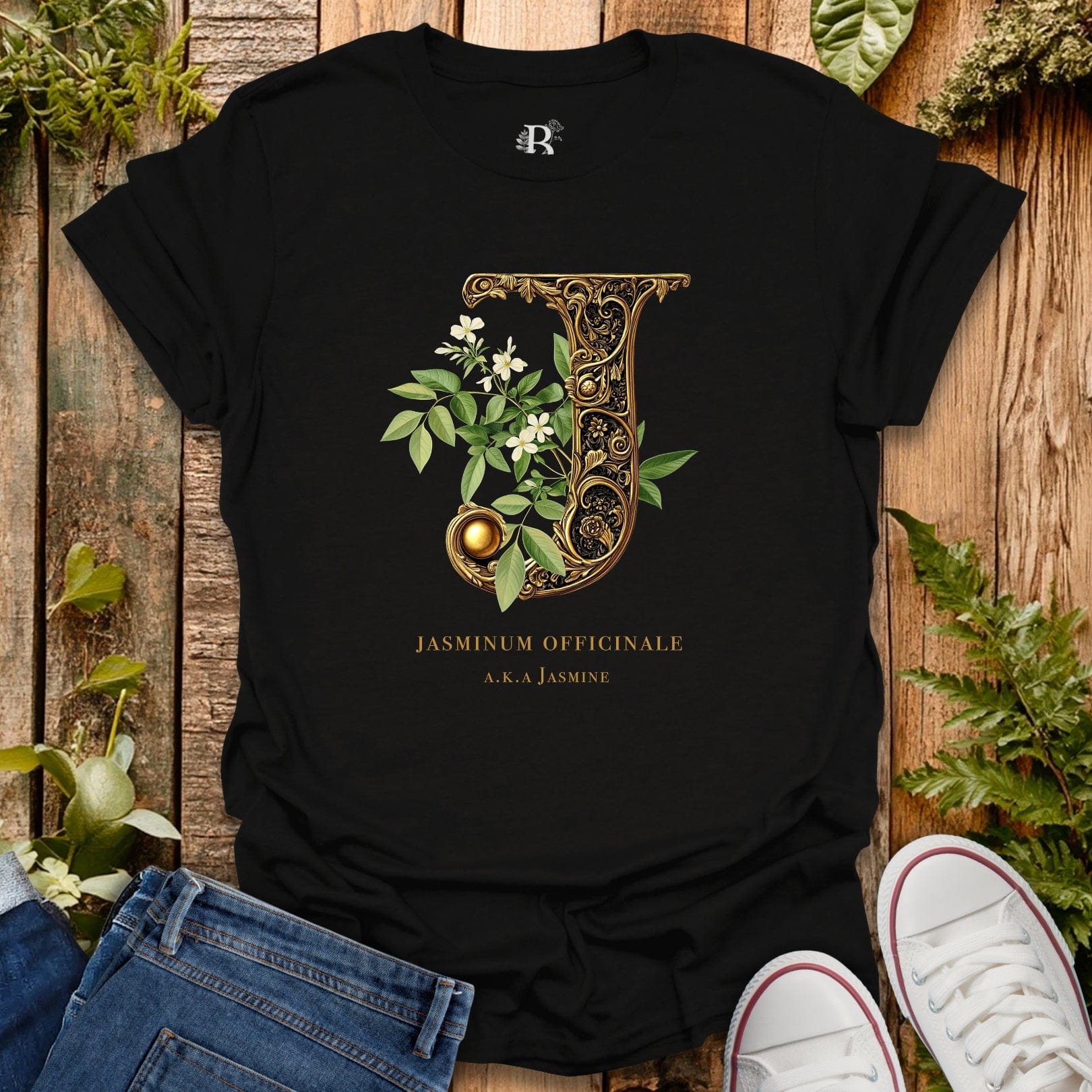 Black t-shirt with decorative letter 'J' design on a wooden surface with plants.