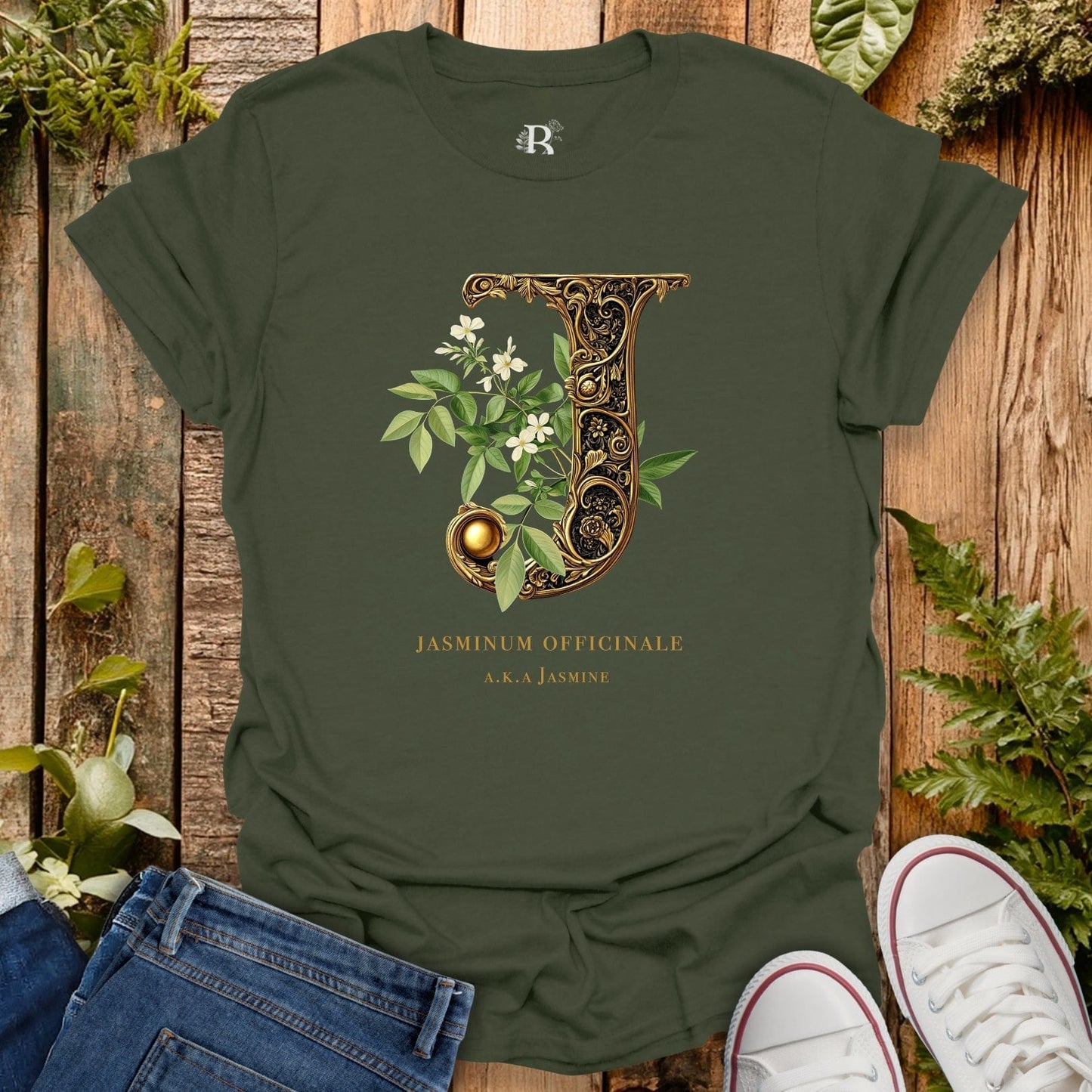 Green t-shirt with decorative letter 'J' design on a wooden surface with plants.