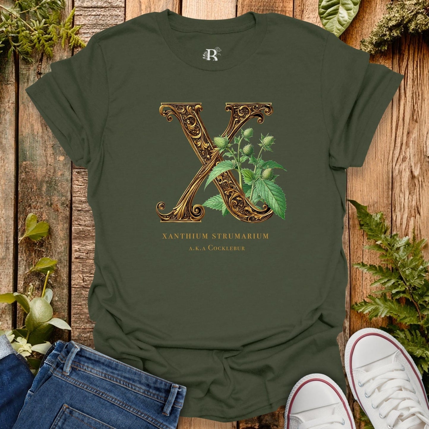 Green t-shirt with decorative letter 'X' and plant design on a wooden background