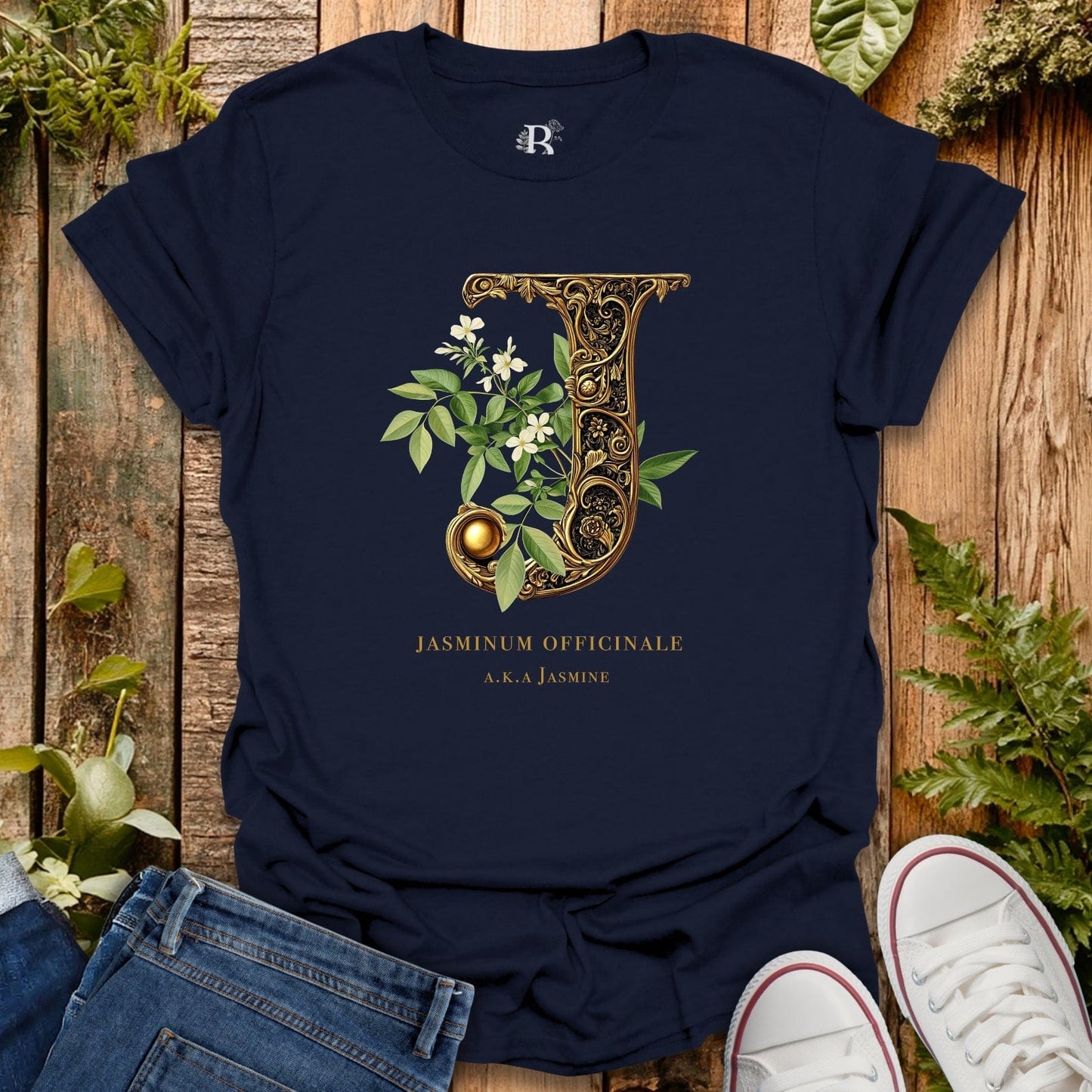 Navy blue t-shirt with decorative letter 'J' design on a wooden surface with plants.