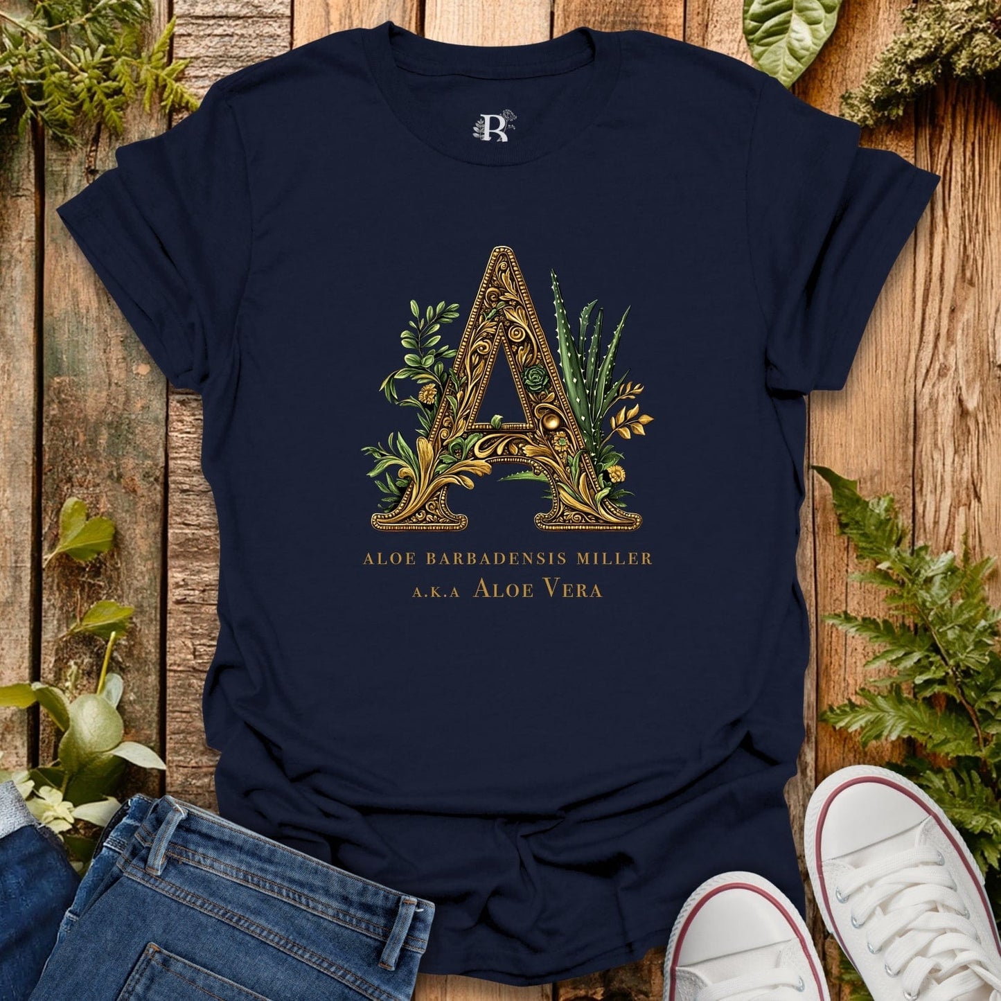 Navy blue t-shirt with decorative letter 'A' design on a wooden surface with plants.