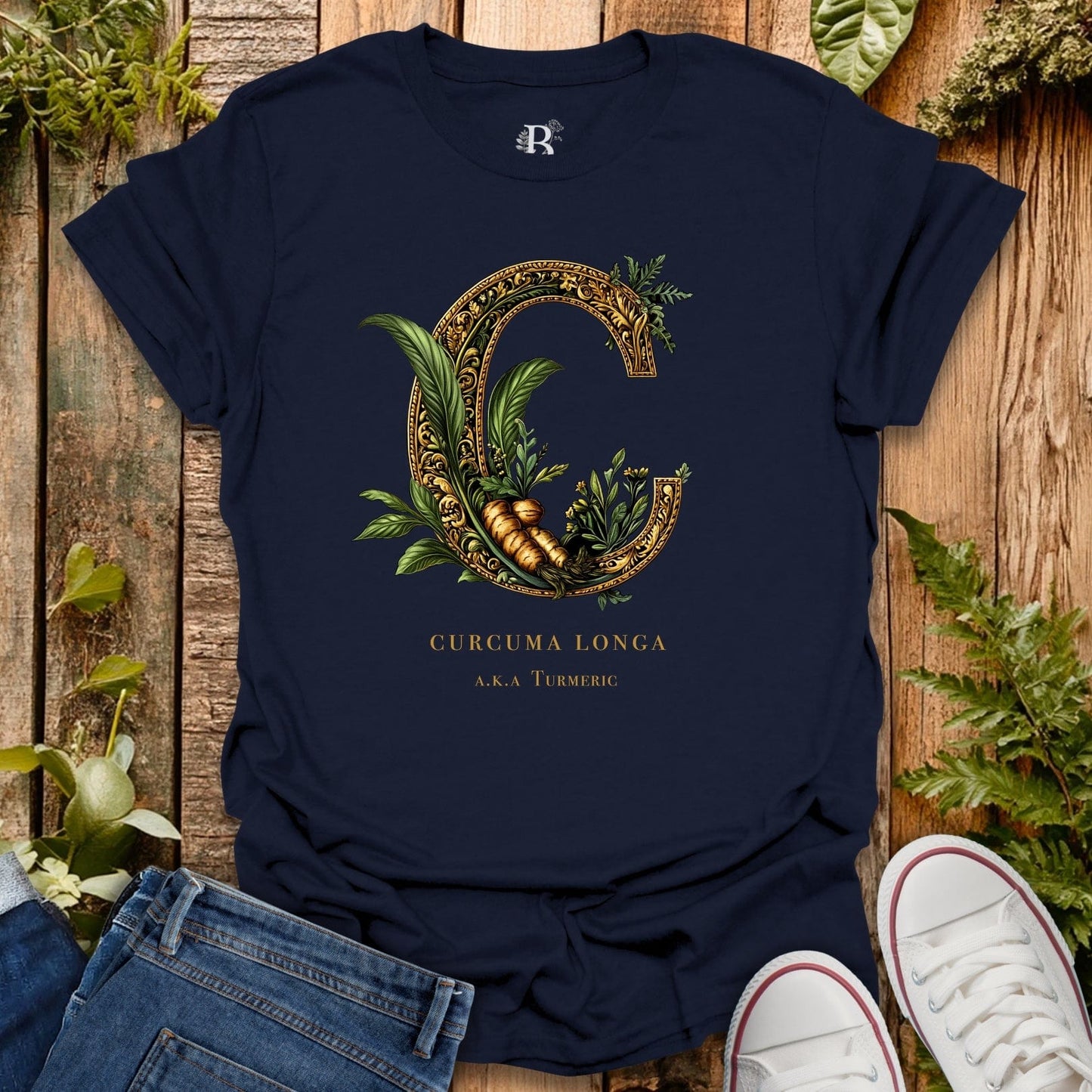 Navy blue t-shirt with decorative letter 'C' design featuring plants on a wooden surface.