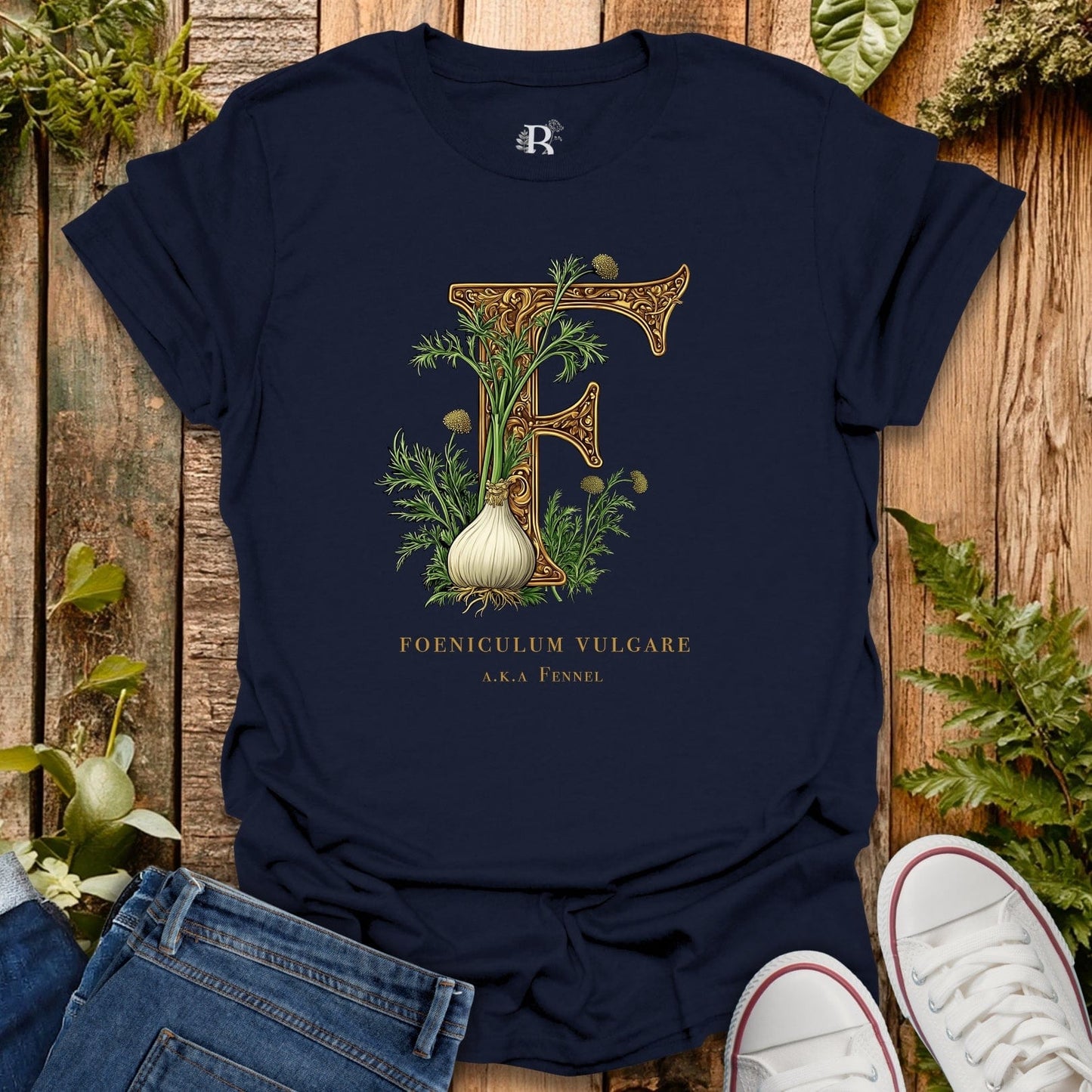 Navy blue t-shirt with botanical 'F' design on a wooden surface with plants.