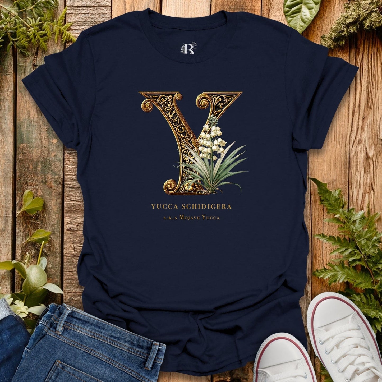 Navy blue t-shirt with decorative letter 'Y' design on a wooden surface with plants.