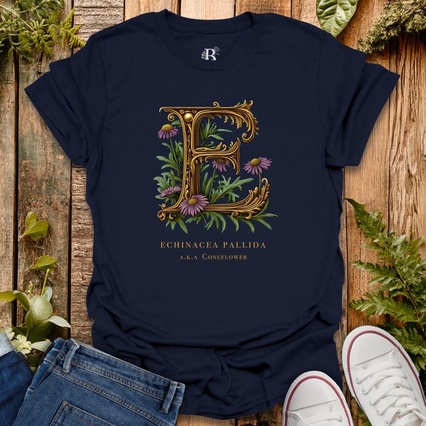 Navy blue t-shirt with floral letter 'E' design on a wooden surface with plants.