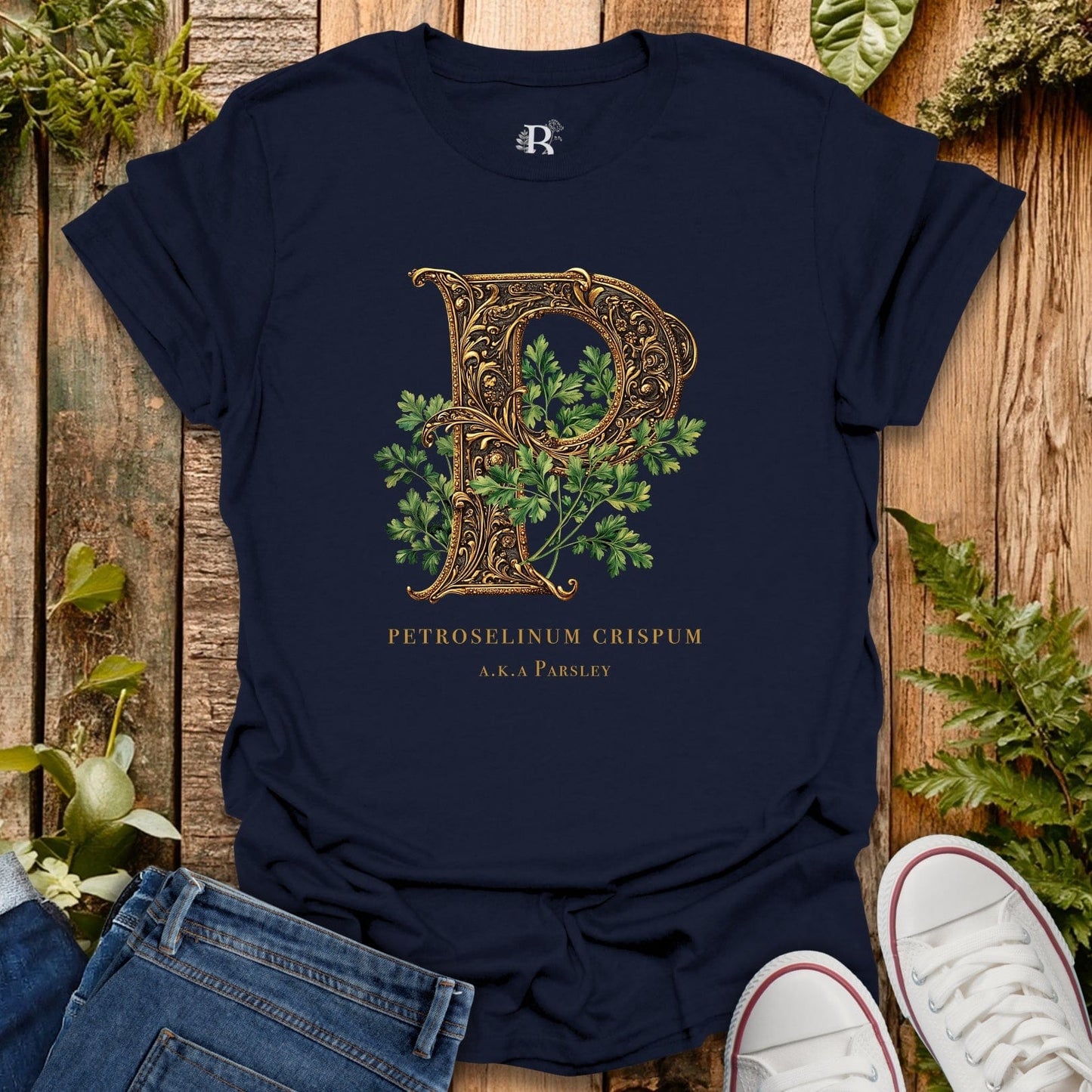 Navy blue t-shirt with decorative letter 'P' design on a wooden surface with plants.