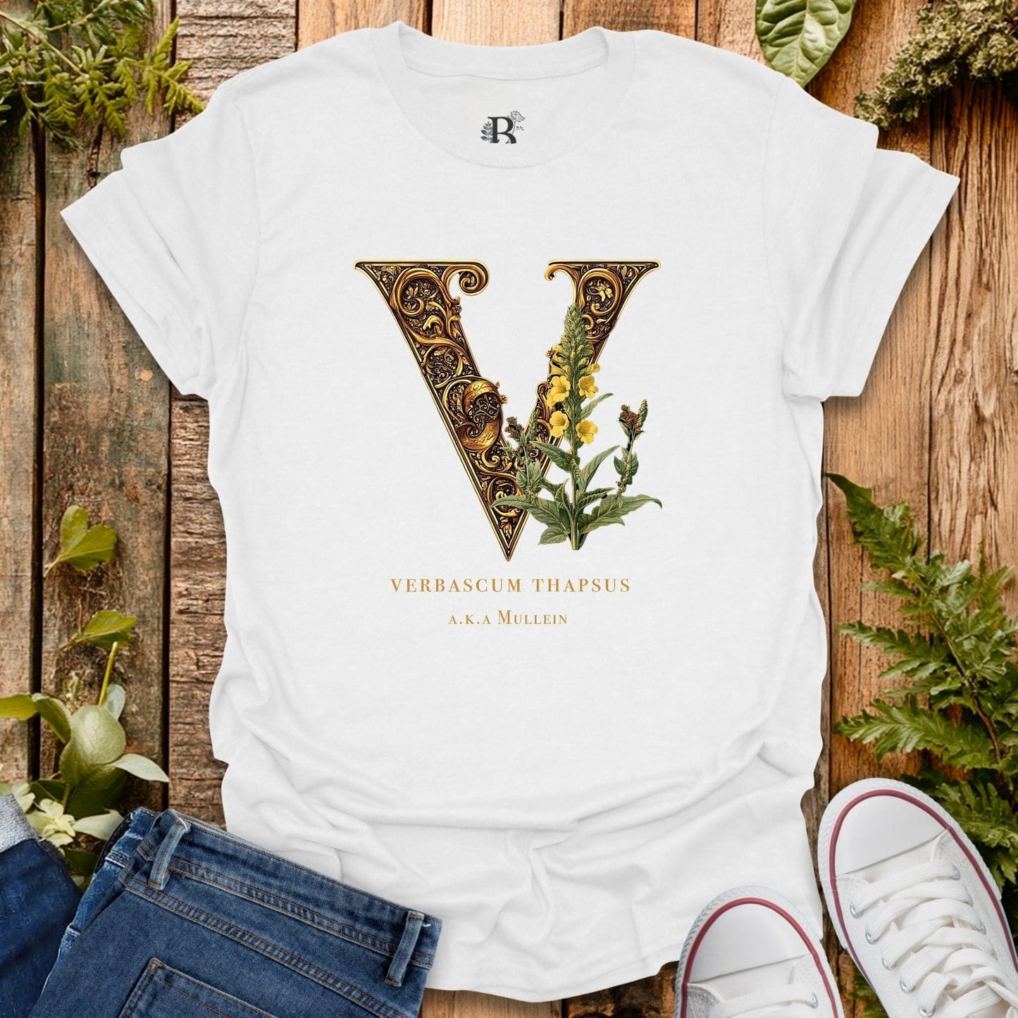 White t-shirt with decorative letter 'V' design on a wooden surface with plants.