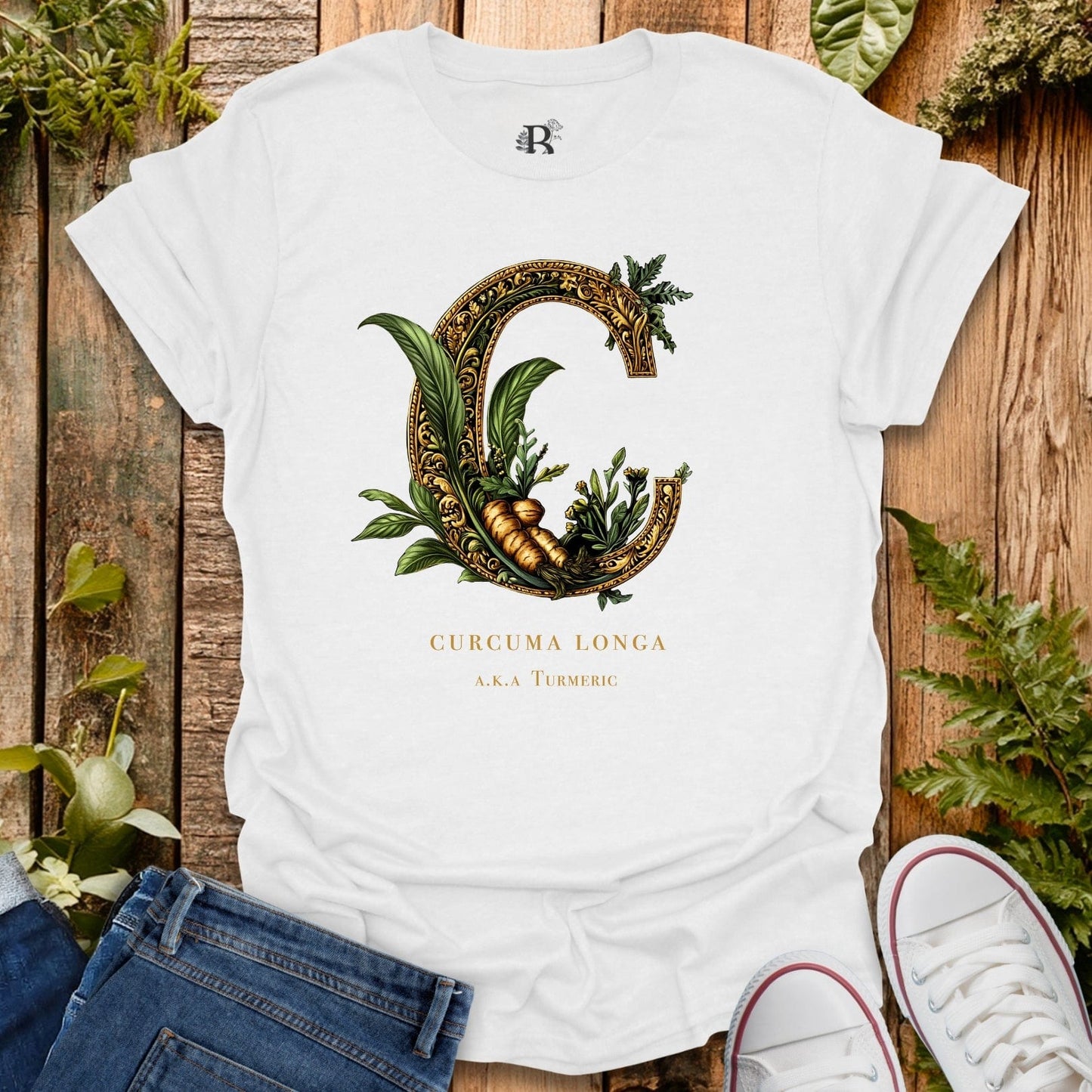 White t-shirt with decorative letter 'C' design featuring plants on a wooden surface.
