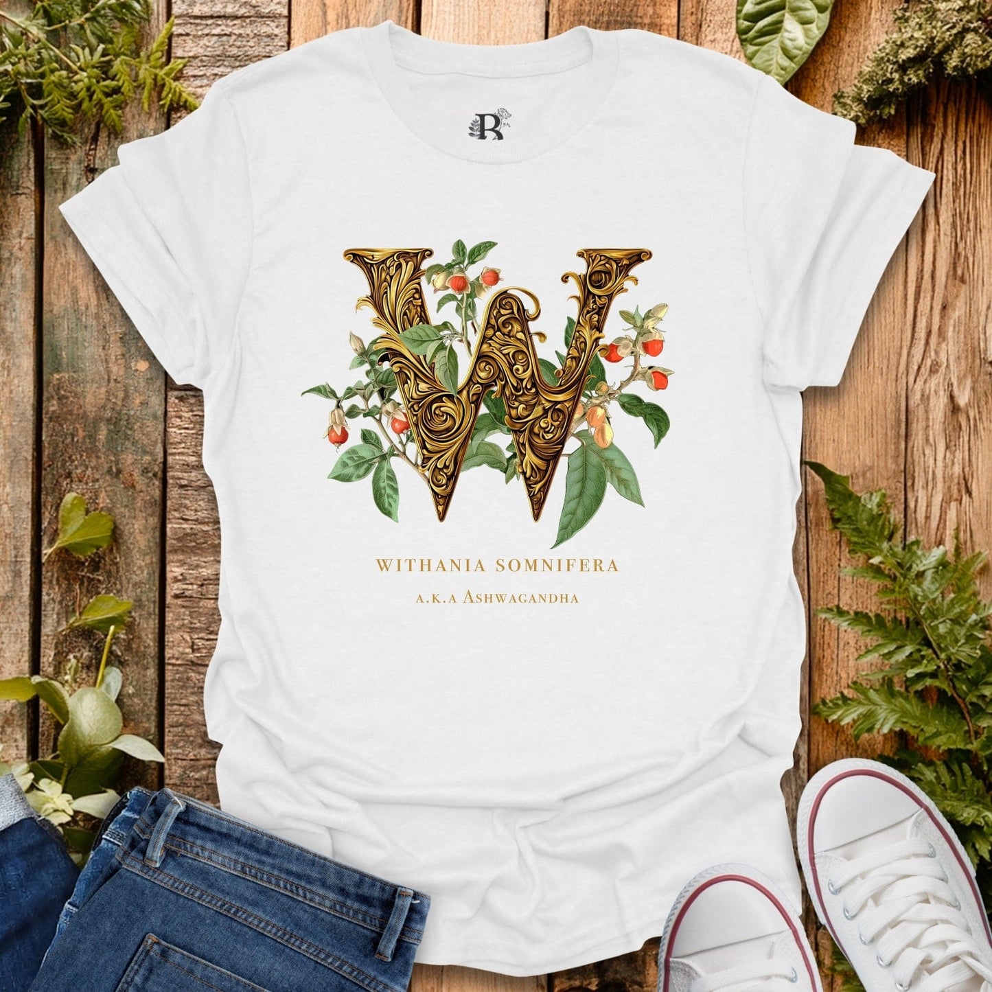 White t-shirt with decorative letter 'W' design on a wooden surface with plants.