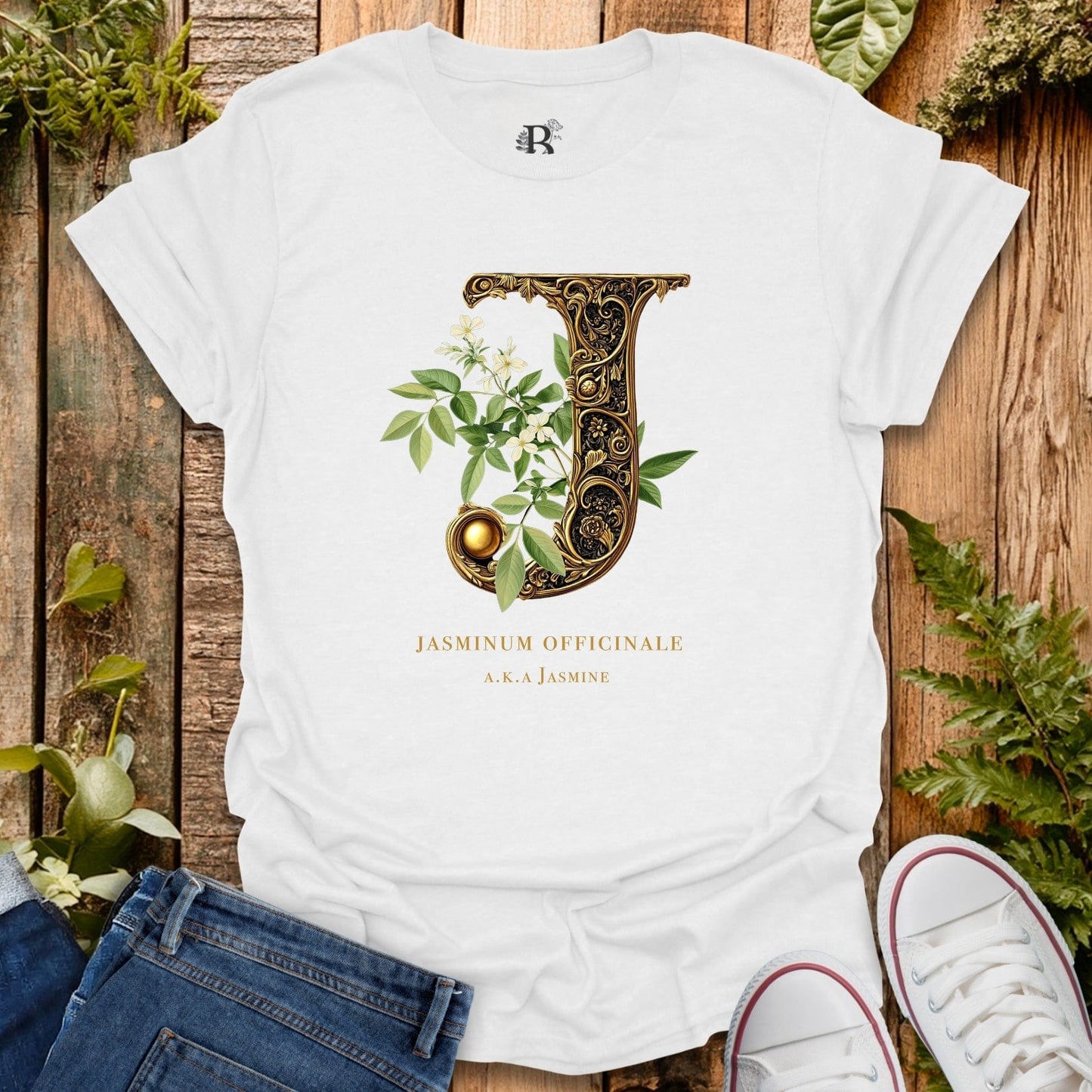 White t-shirt with decorative letter 'J' design on a wooden surface with plants.