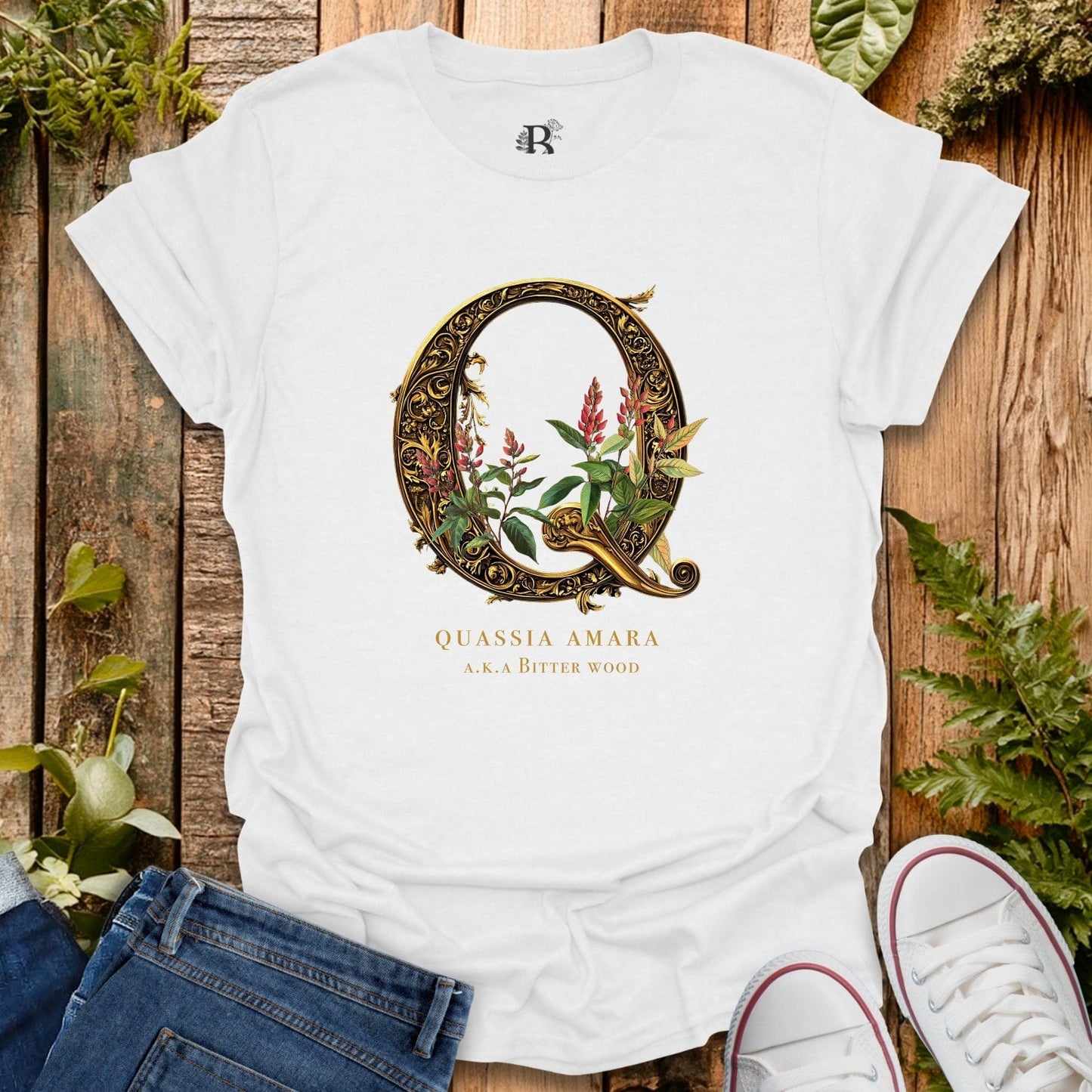 White t-shirt with decorative letter 'Q' design on a wooden surface with plants.