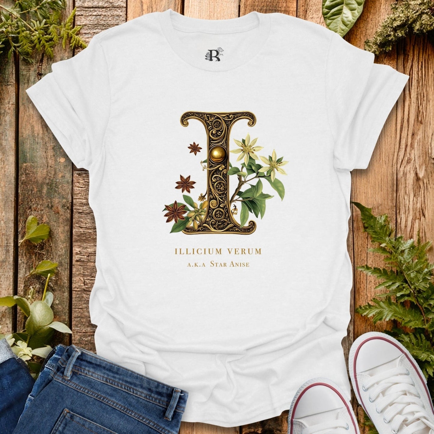White t-shirt with decorative letter 'L' design on a wooden surface with plants.