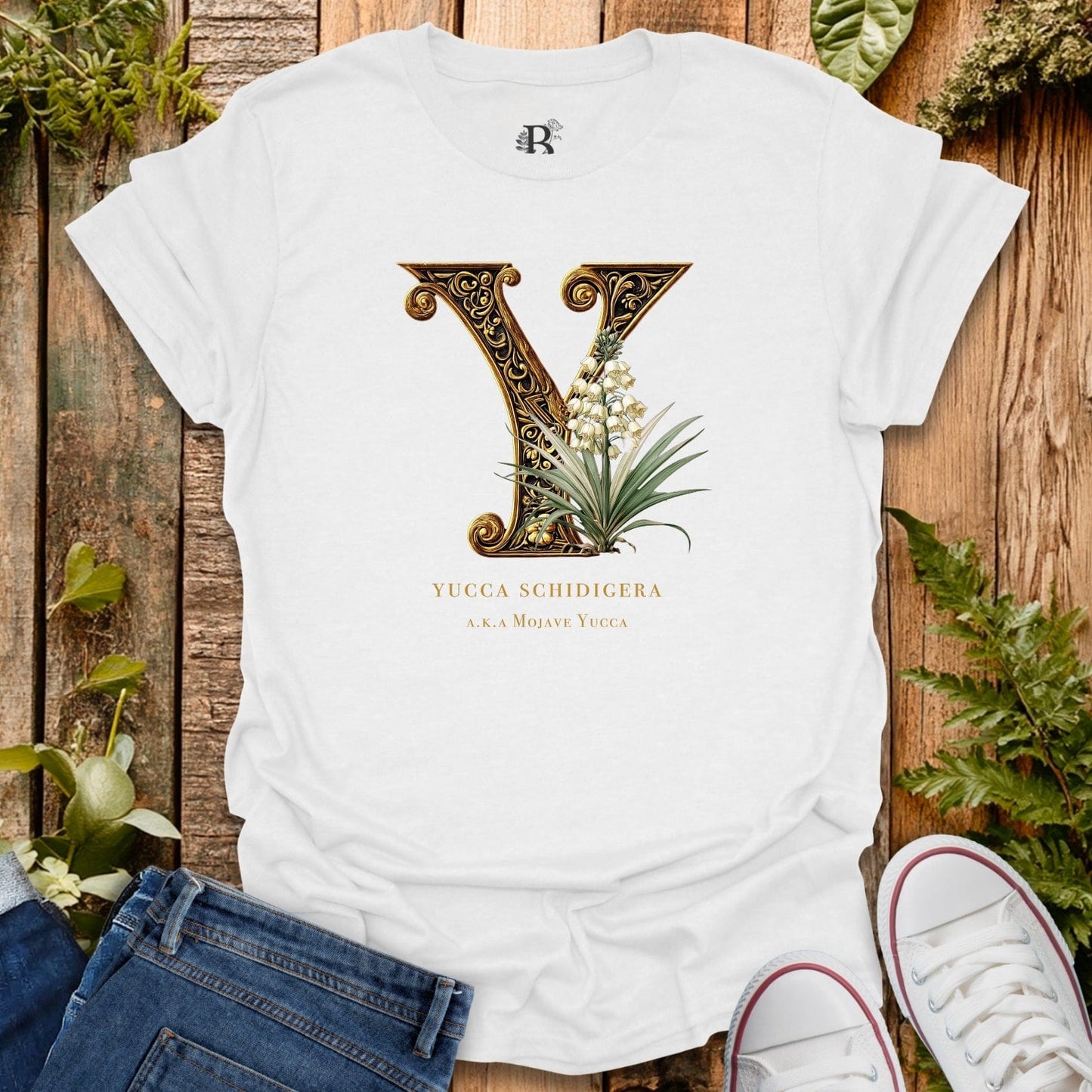 White t-shirt with decorative letter 'Y' design on a wooden surface with plants.