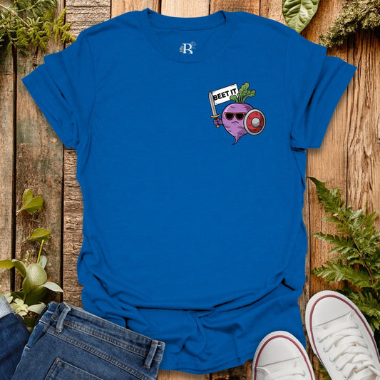 Blue t-shirt with a graphic design on a wooden surface with plants.