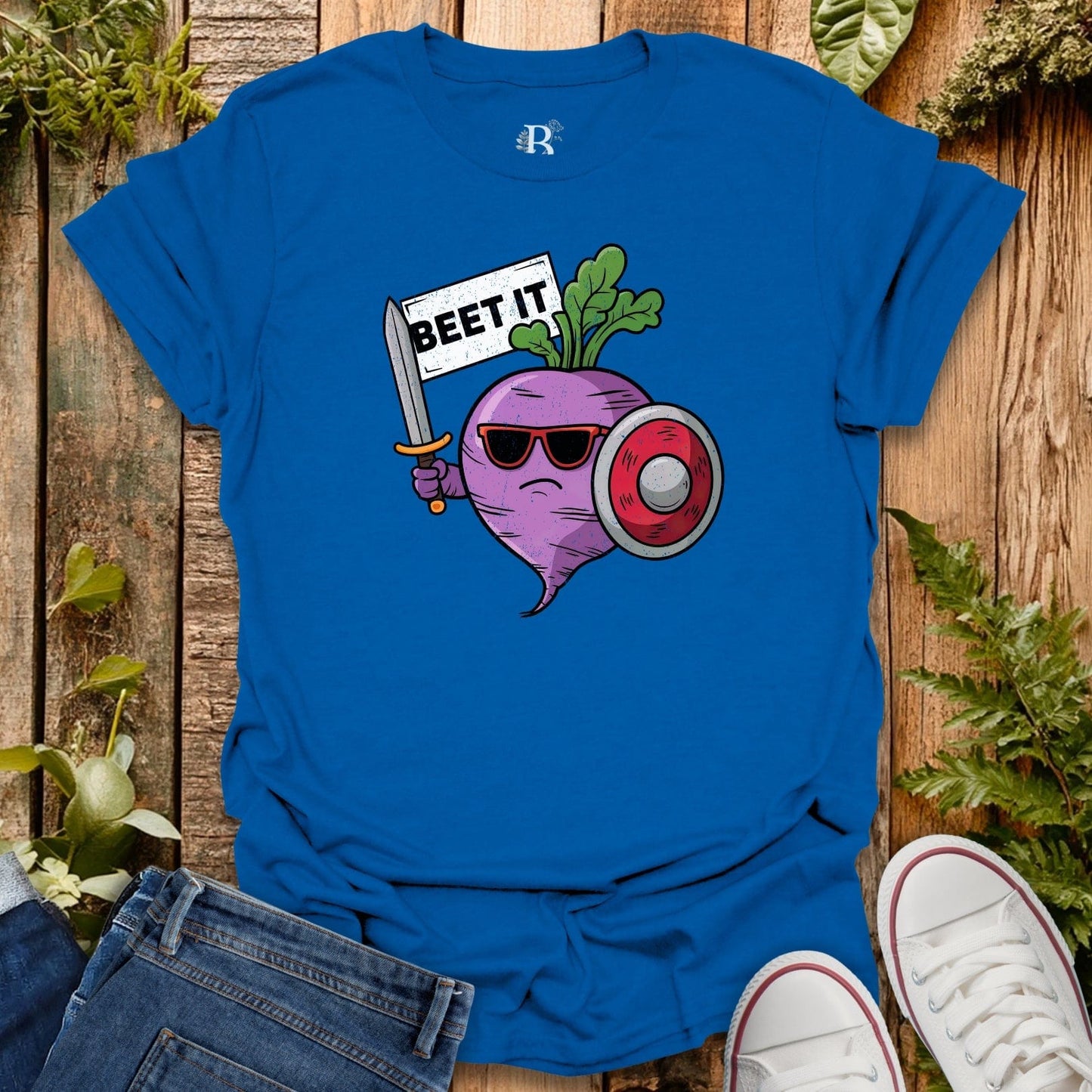 Blue t-shirt with a cartoon beet holding a sign and sword on a wooden background
