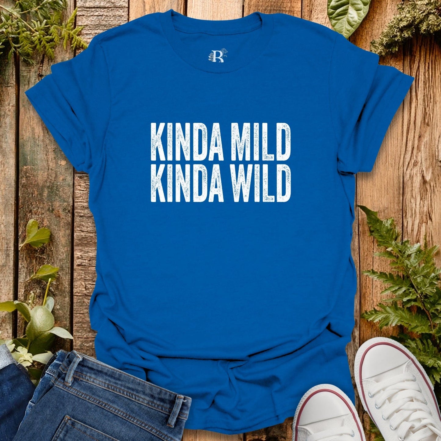 Blue t-shirt with 'KINDA MILD KINDA WILD' text on a wooden surface with jeans and sneakers.