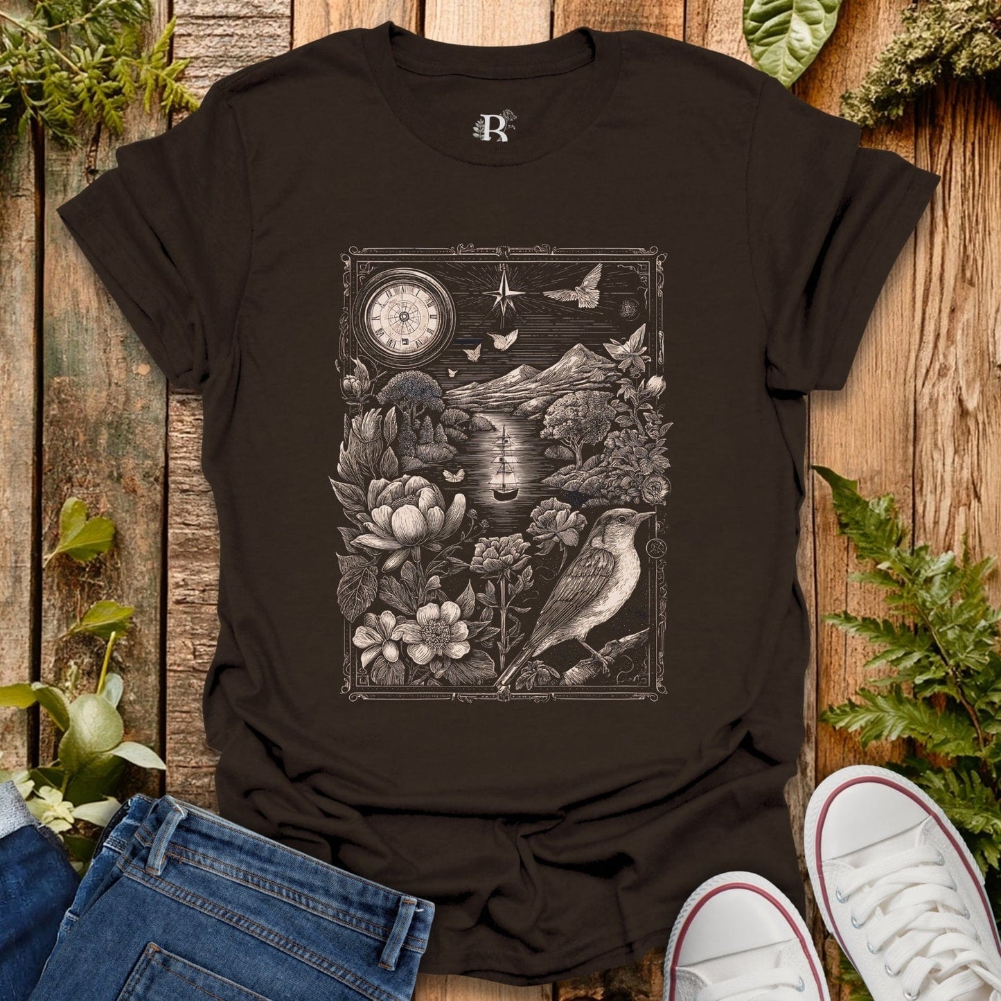 Black t-shirt with nature-themed design on a wooden surface with plants.