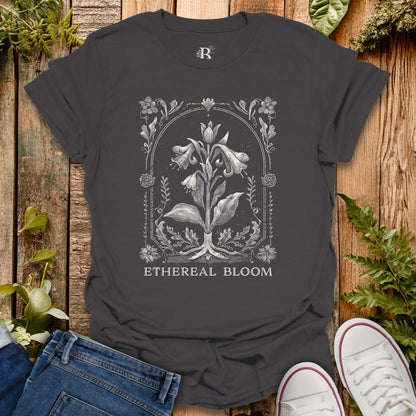 Black t-shirt with floral design and 'Ethereal Bloom' text on a wooden surface with plants.