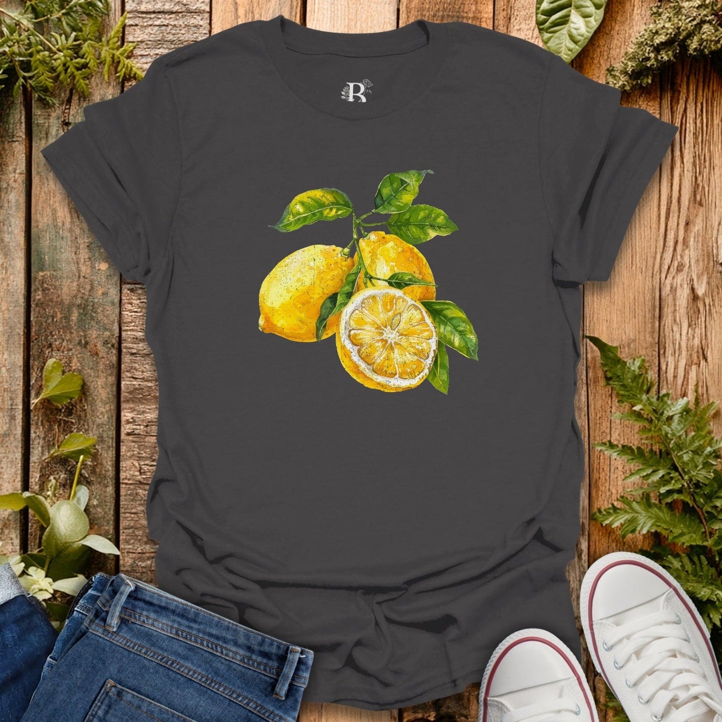 Black t-shirt with lemon design on a wooden surface with jeans and sneakers.