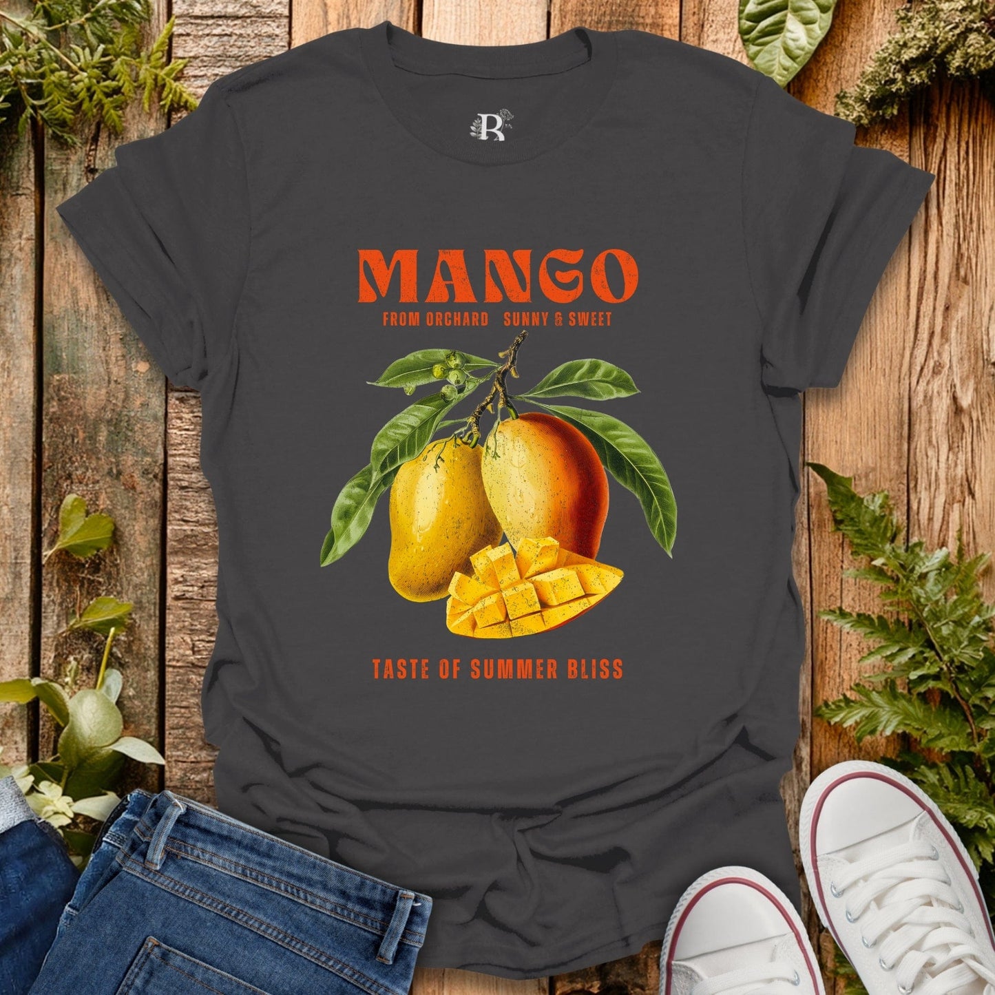 Gray t-shirt with mango graphic and text on a wooden surface with jeans and shoes.