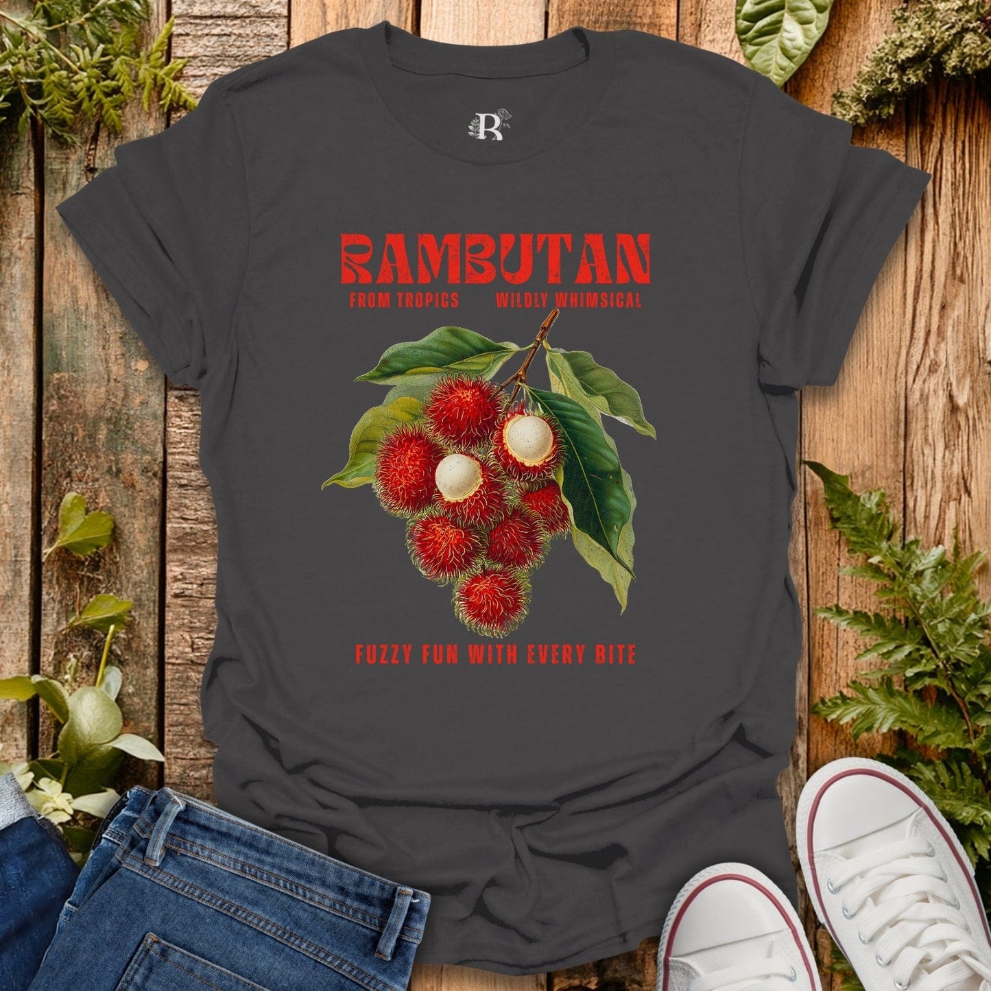 Gray t-shirt with rambutan graphic and text on a wooden surface with jeans and shoes.