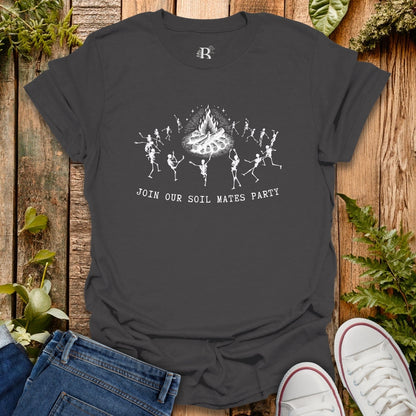 Black t-shirt with skeleton design and text on a wooden surface with plants.