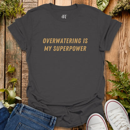 Black t-shirt with 'Overwatering is my Superpower' text on a wooden background with plants.