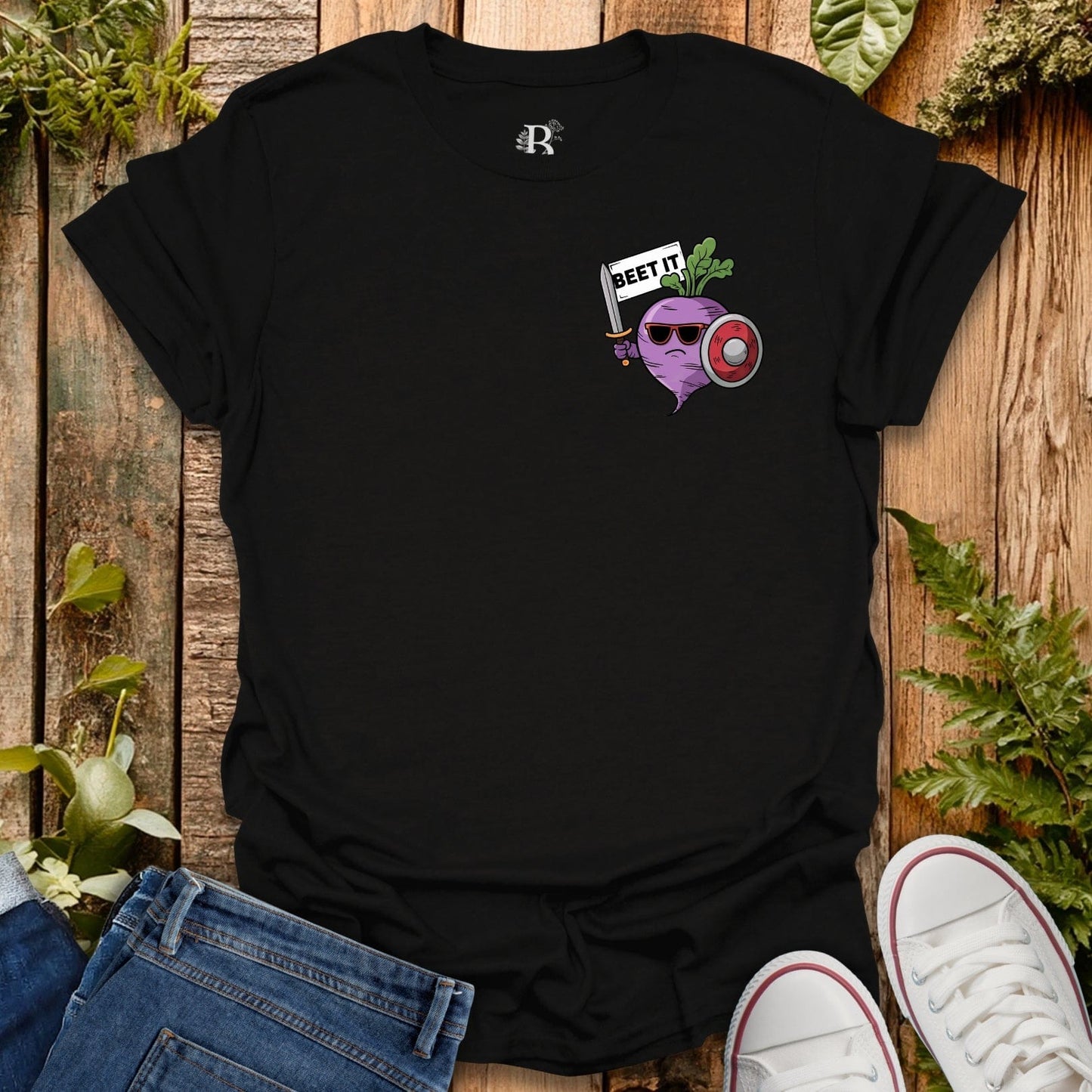 Black t-shirt with a graphic design on a wooden surface with plants