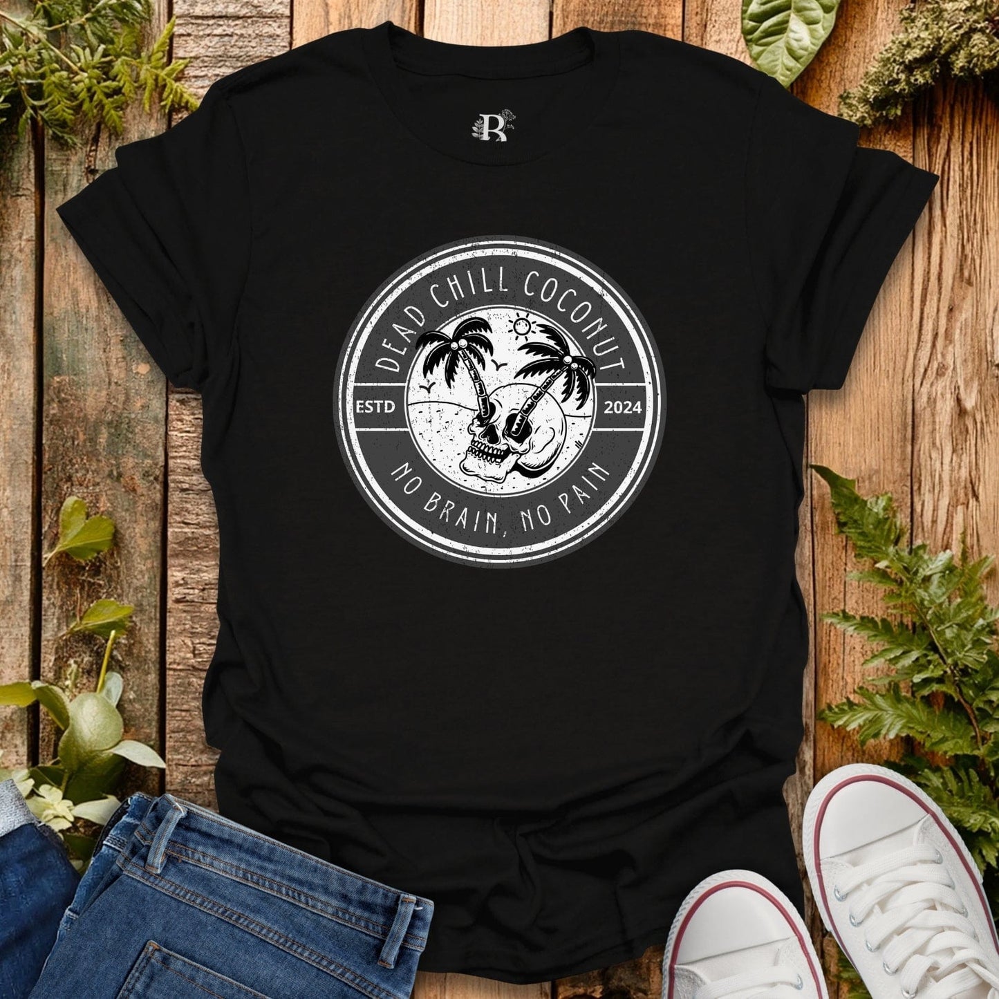 Black t-shirt with a graphic design on a wooden surface with plants.