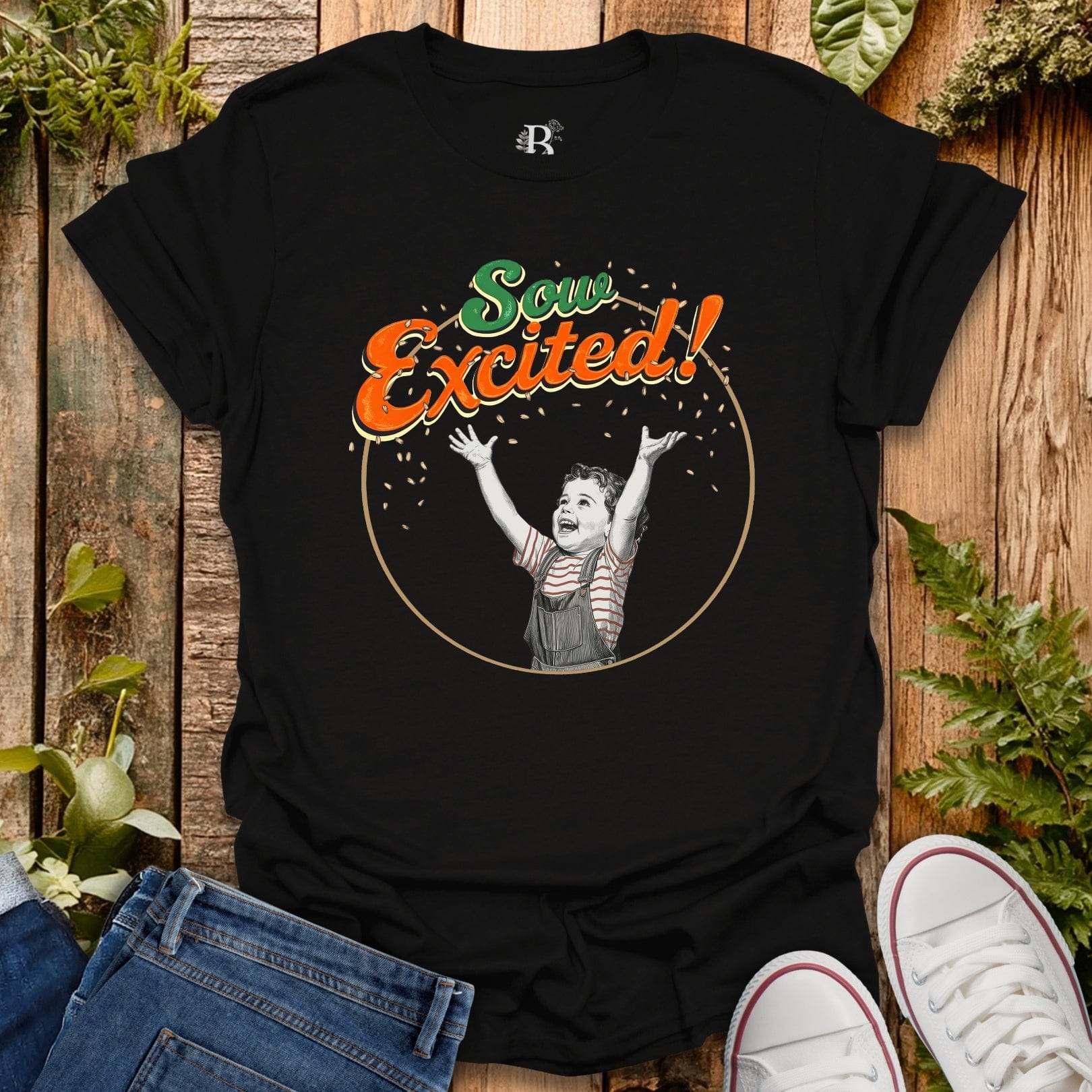 Black t-shirt with 'Sow Excited!' graphic on a wooden surface with plants.
