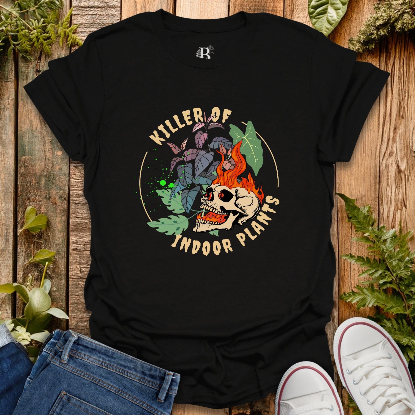 Black t-shirt with skull and plant design on a wooden surface with plants around