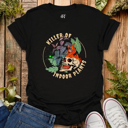 Black t-shirt with skull and plant design on a wooden surface with plants around
