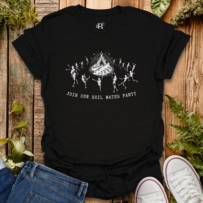 Black t-shirt with skeleton design and text on a wooden surface with plants.