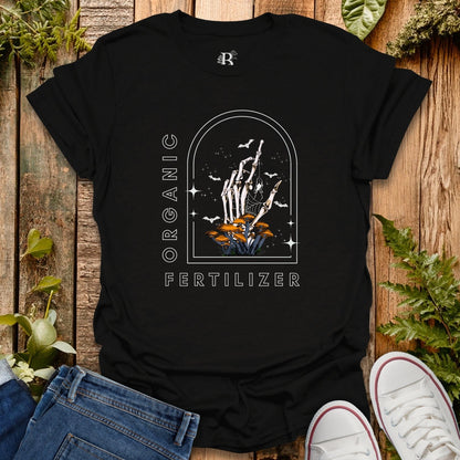 Black t-shirt with a graphic design on a wooden surface with plants