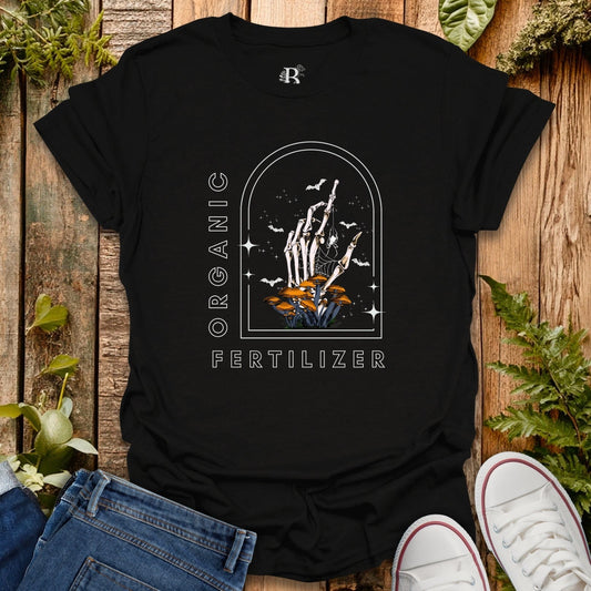 Black t-shirt with a graphic design on a wooden surface with plants