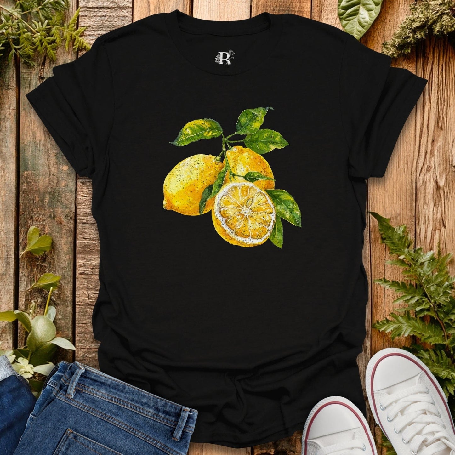 Black t-shirt with lemon design on a wooden surface with jeans and shoes.