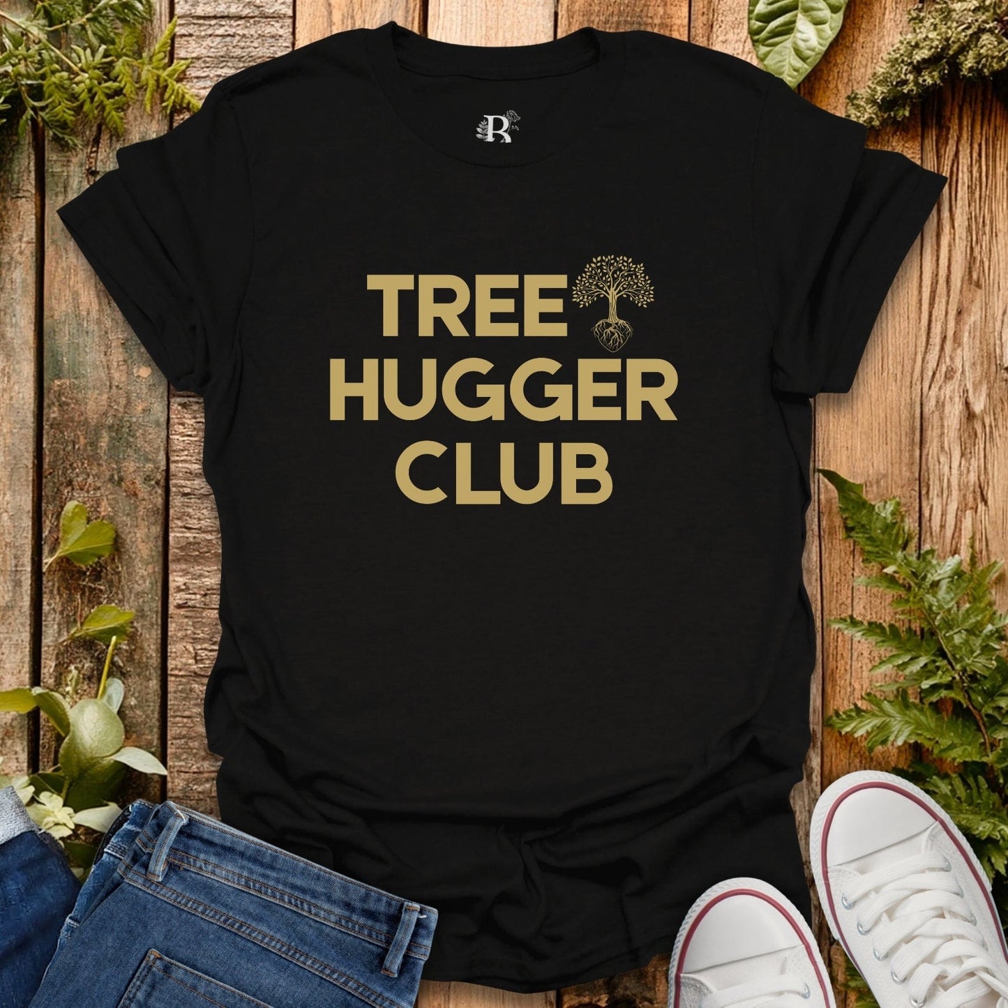 Black t-shirt with 'Tree Hugger Club' text on a wooden surface with plants.