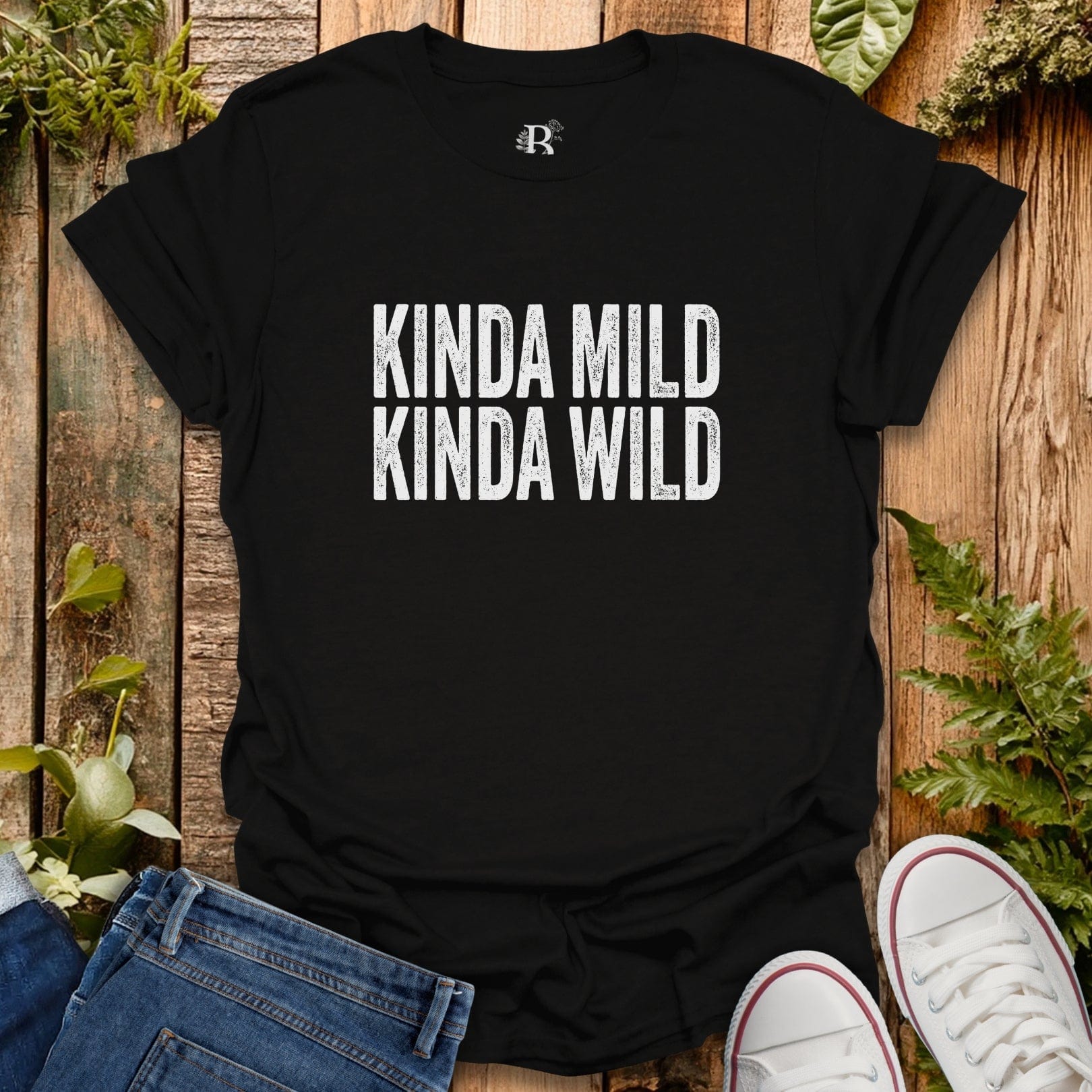 Black t-shirt with 'KINDA MILD KINDA WILD' text on a wooden surface with jeans and sneakers.