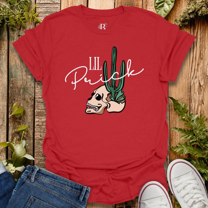 Red t-shirt with skull and cactus design on a wooden surface with plants.