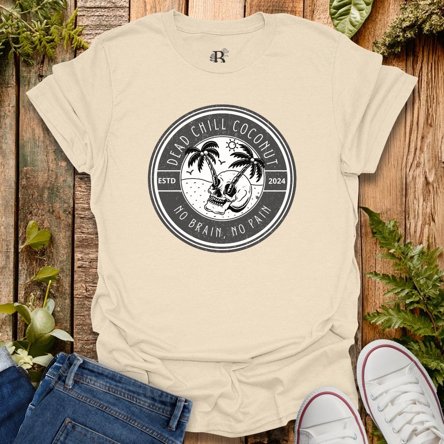 Beige t-shirt with a graphic design on a wooden surface with plants.