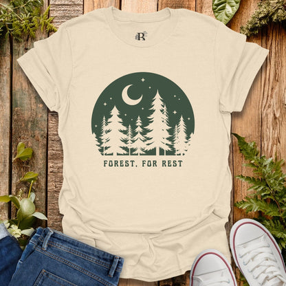 Beige t-shirt with forest graphic and 'Forest, For Rest' text on a wooden background