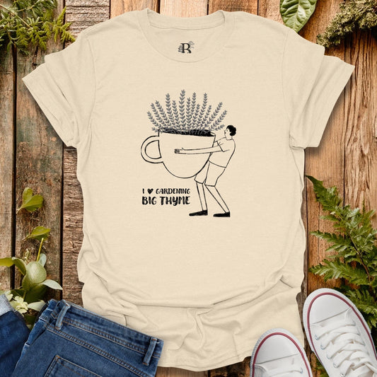 Beige t-shirt with a graphic design of a person holding a large pot of thyme, placed on a wooden surface with plants around.