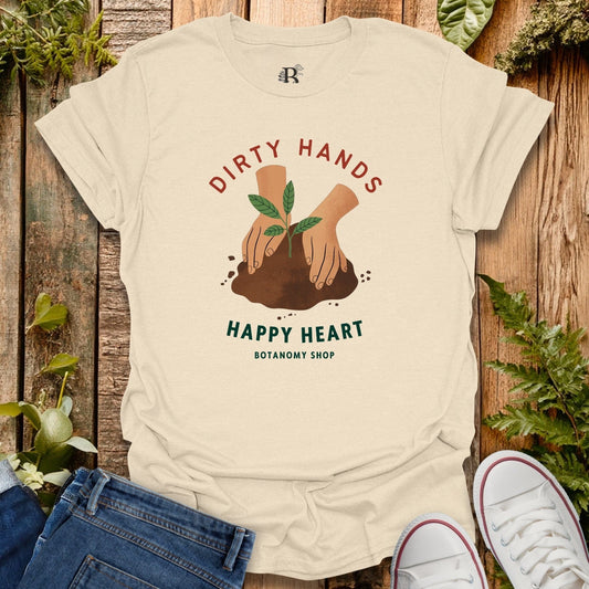 Beige t-shirt with 'Dirty Hands Happy Heart' graphic on a wooden background with plants.