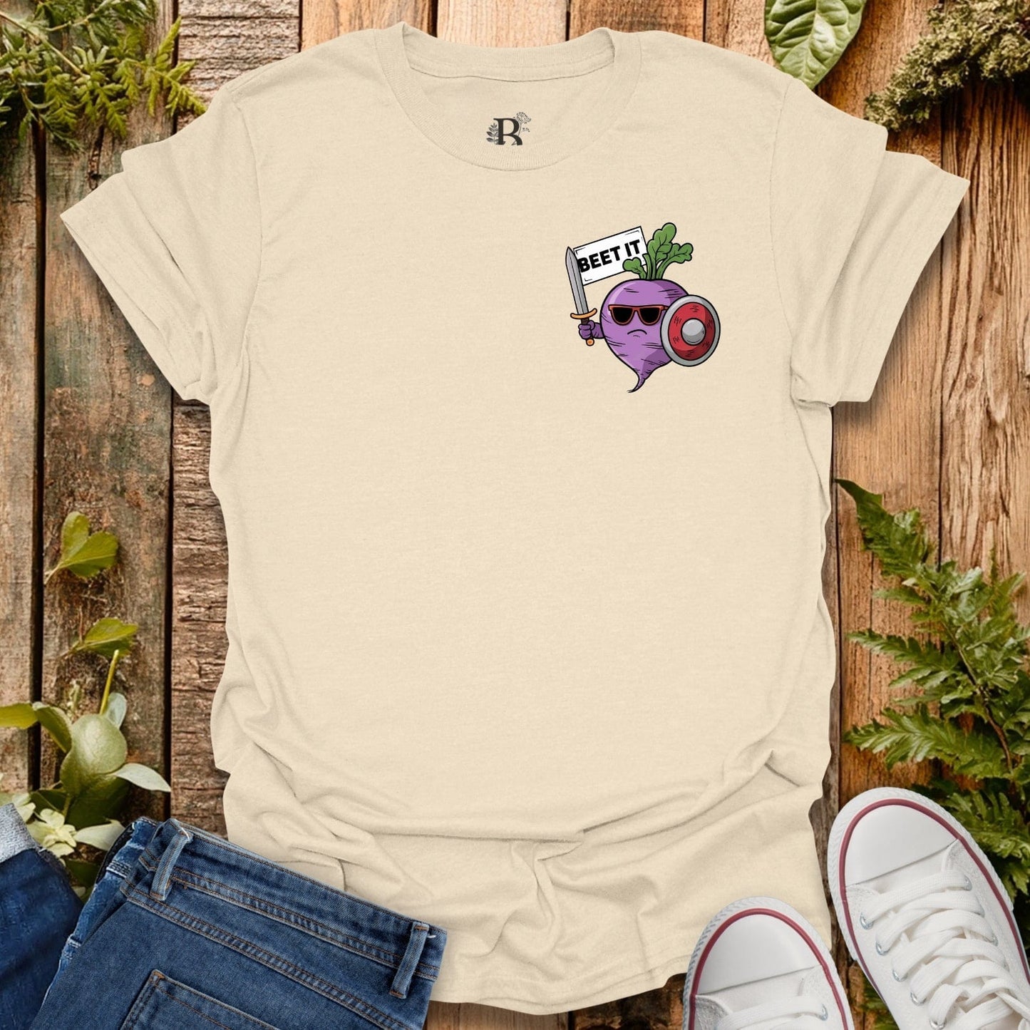 Beige t-shirt with graphic design on a wooden surface with plants