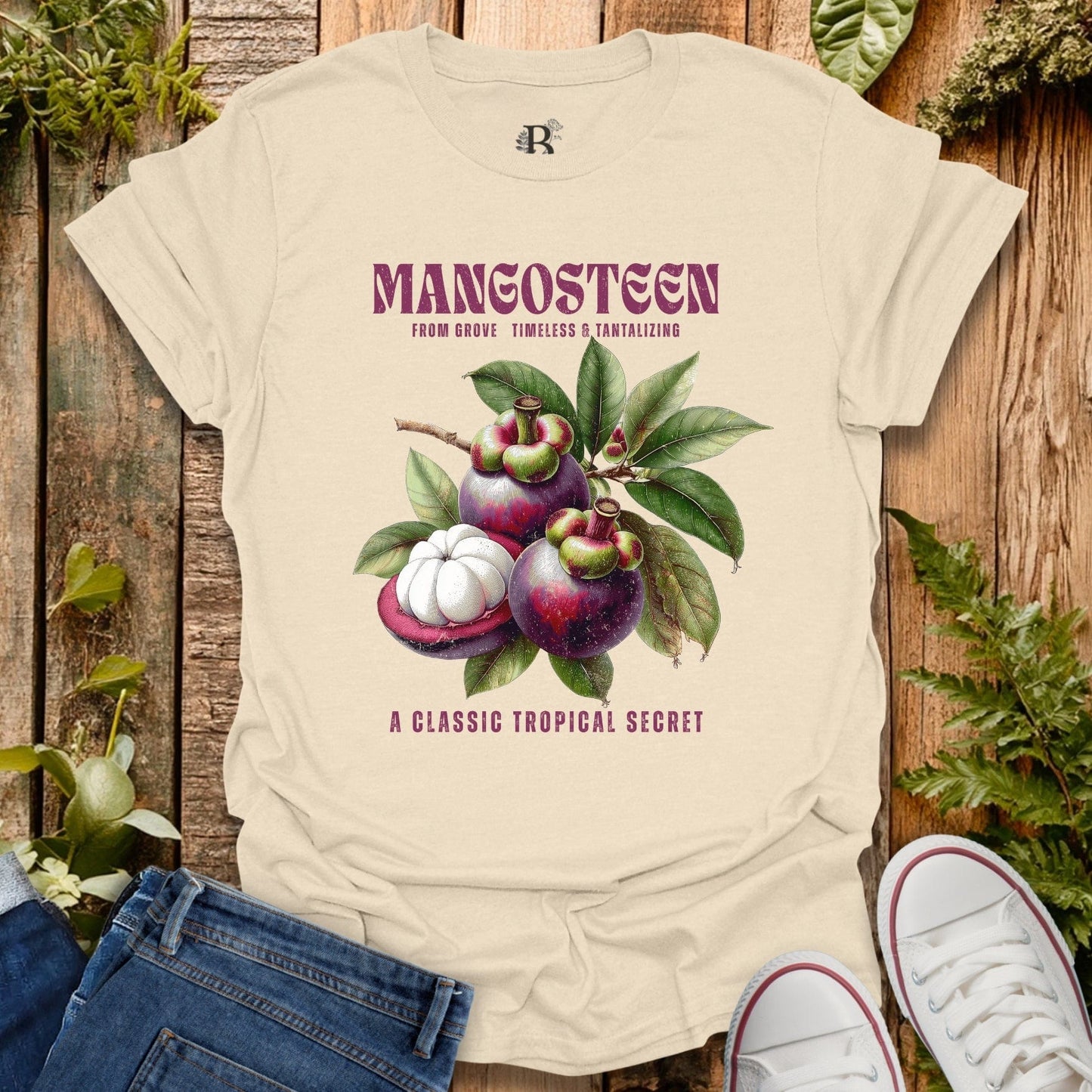 Beige t-shirt with mangosteen graphic and text on a wooden background