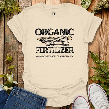 Beige t-shirt with 'Organic Fertilizer' graphic on a wooden background with plants.