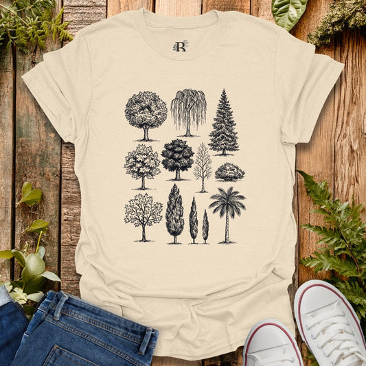 Beige t-shirt with tree illustrations on a wooden surface with plants.