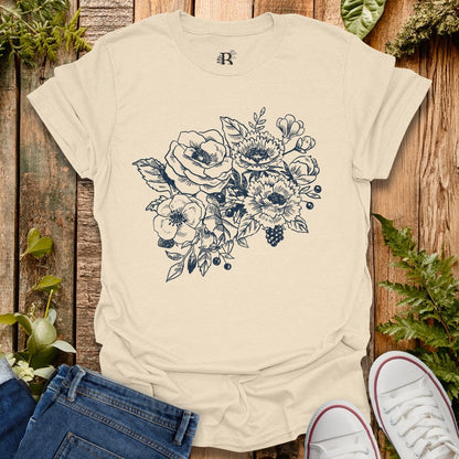 Beige t-shirt with floral design on a wooden surface with plants.
